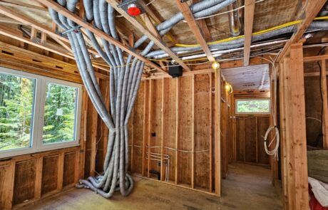 Interior view of a residential construction site with exposed wall framing and ducting for the HRV unit.