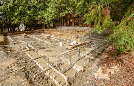 Photo of a in-progress foundation pour with concrete setting and excavation equipment in the background.