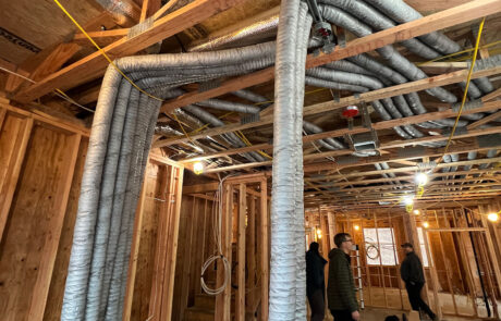 Residential construction site with wooden framing in progress, showing exposed walls and HRV ducting coming from the ceiling.